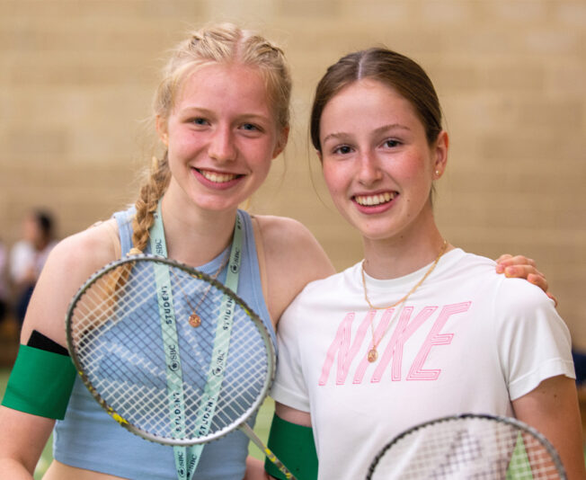 two-girls-smiling-holding-tennis-rackets.j