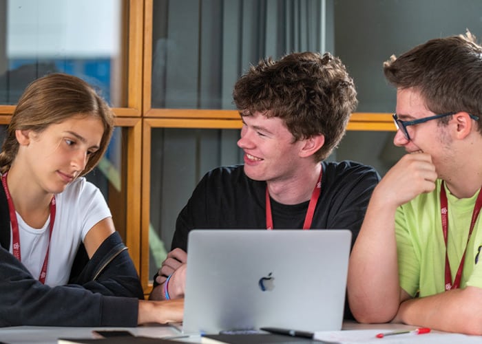 three-students-laughing-using-laptop