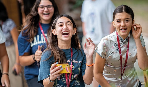 female-summer-school-students-walking-laughing.