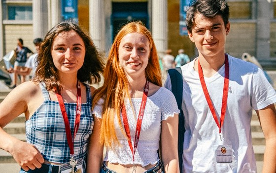 three students outside on a trip smiling