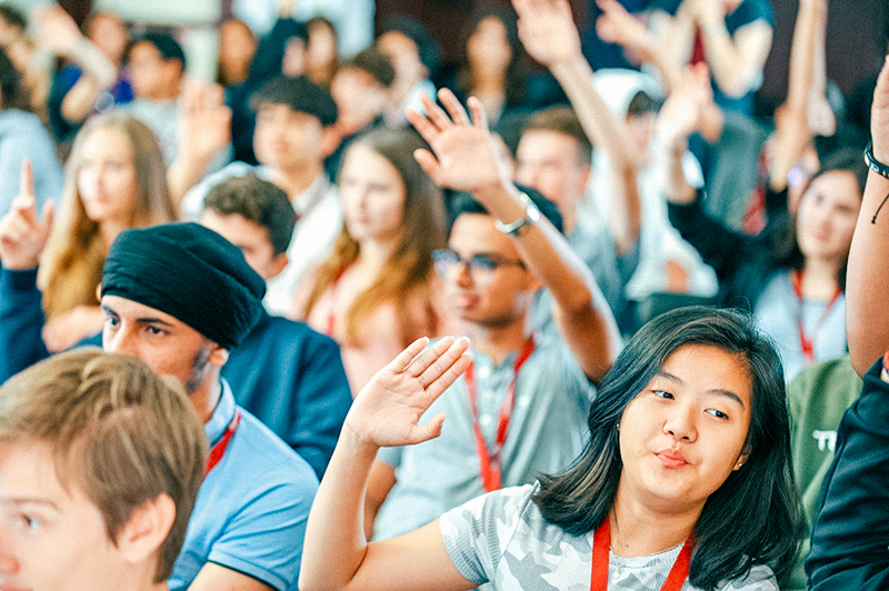students together raising their hands and smiling