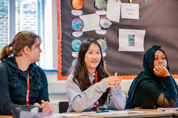 three headington oxford students sat at a desk in a headington oxford classroom