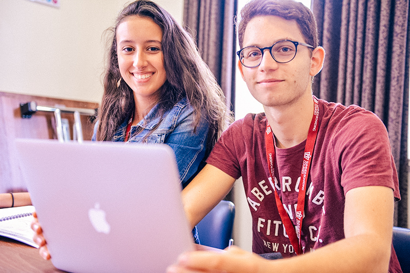 male and female student with a laptop in class