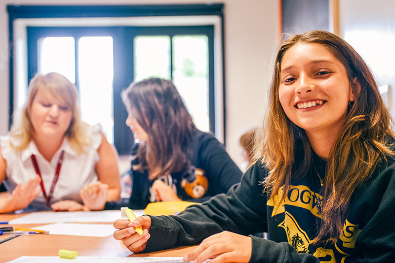 essay writing books for college students smiling student looking at camera out of focus students in background lowres