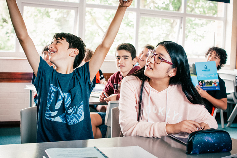 student raising his hands looking happy in class lowres