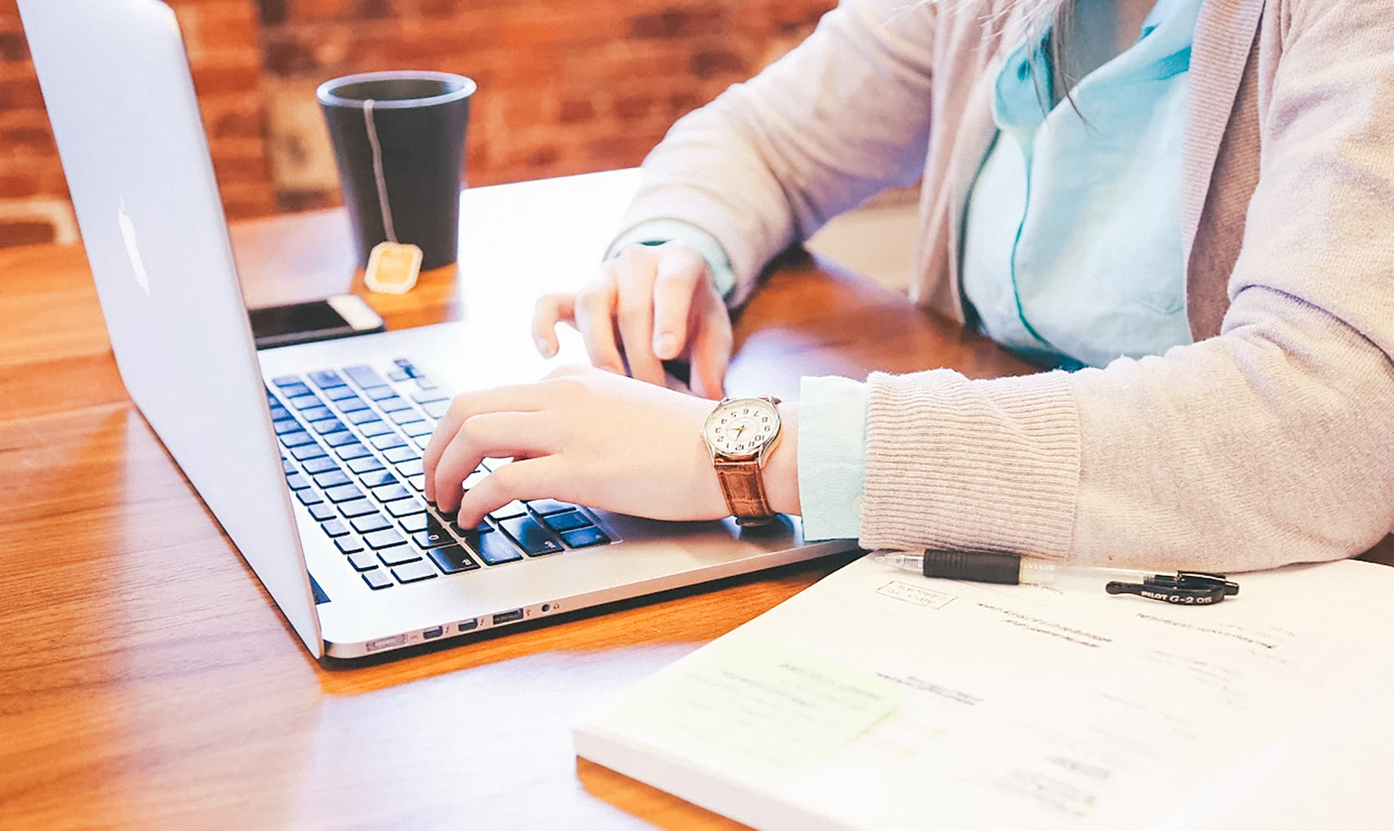 student sat at a laptop with a hot drink working online
