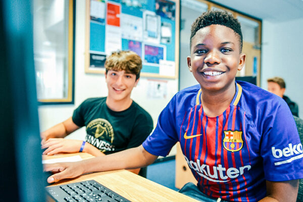 two students sit at a computer working