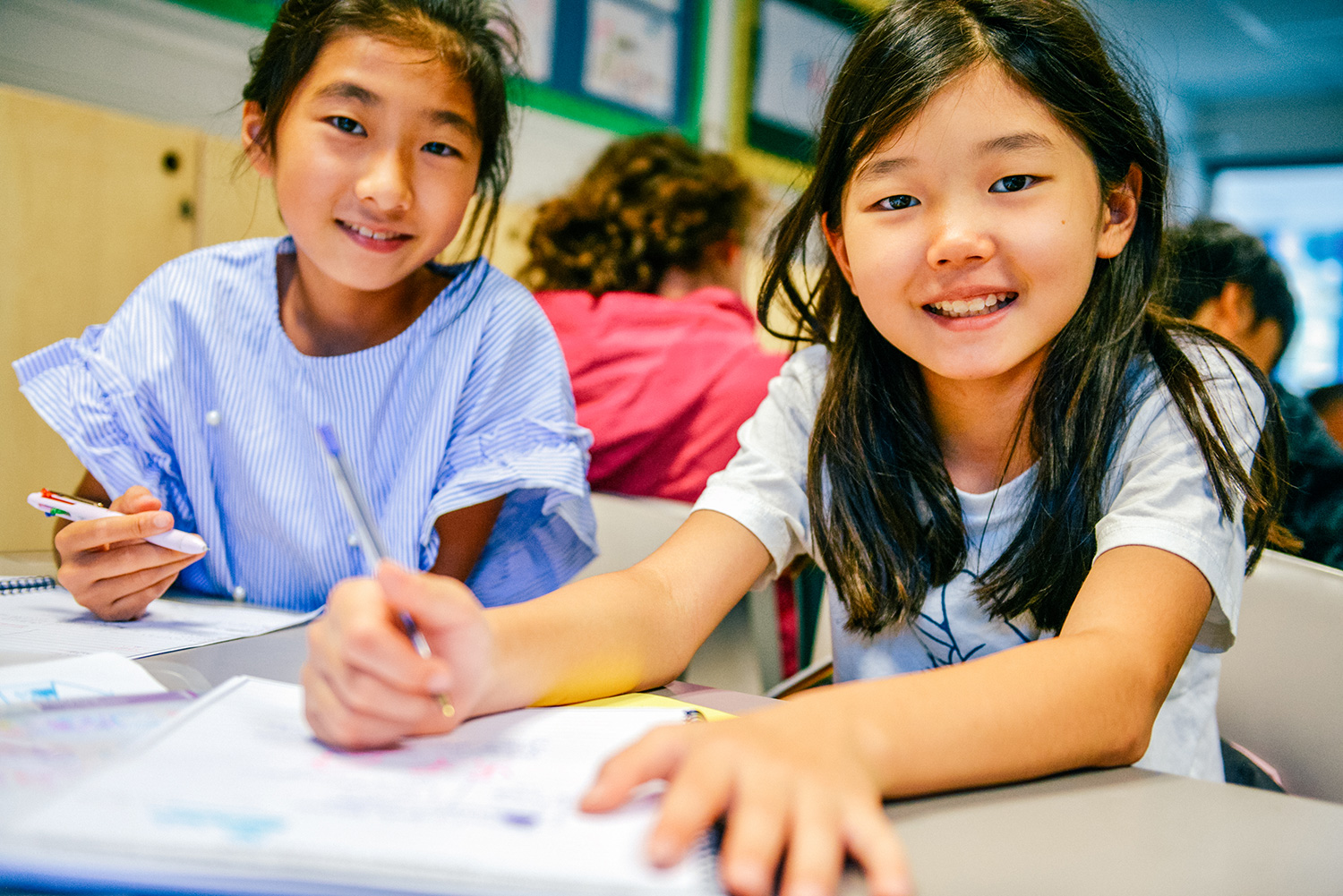 two young sbc students writing in a classroom together