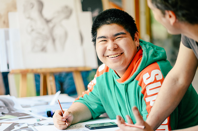 Rochester student in an art class smiling at tutor