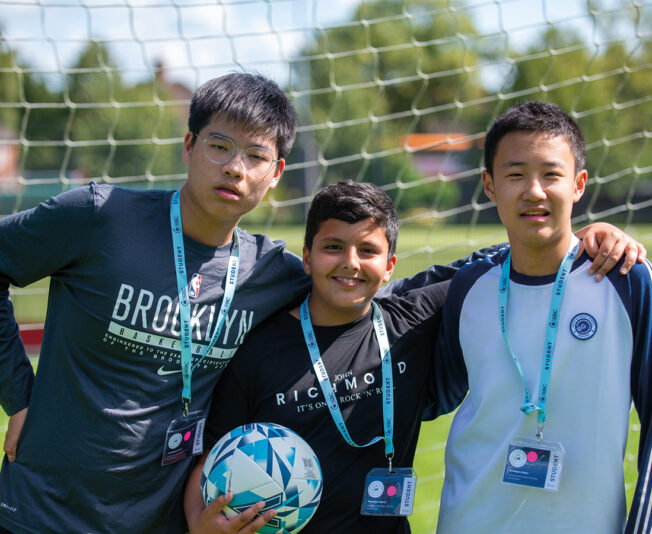 three-male-headington-students-smiling-in-football-net