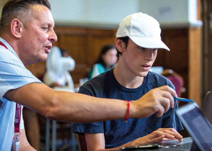 Summer-school-tutor-teaching-computers-to-student.