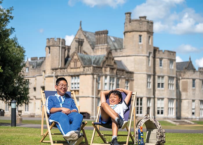 two-canford-students-on-deckchairs-outside-of-school