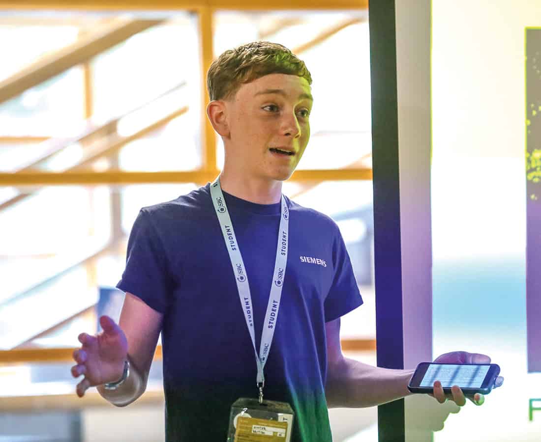 Male student stood up giving a Time to Shine presentation with his arms stretched out