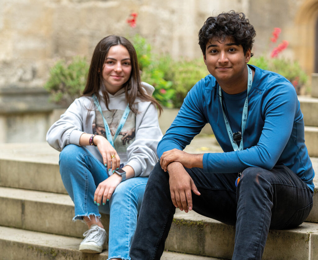 Male & Female Oxford College Students sat outside and smiling at the camera