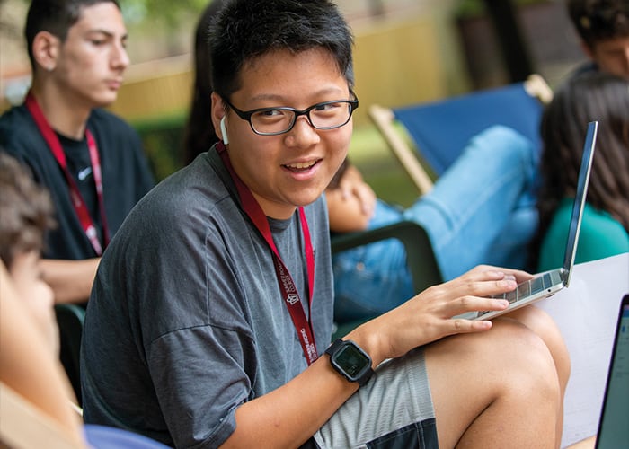 Male student sat outside with his friends about to start some social activities at Oxford College