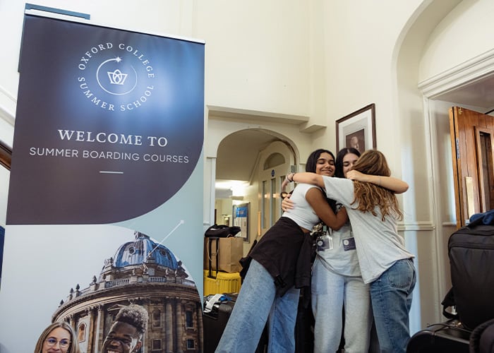 Three female students hugging in the Wycliffe Oxford College building
