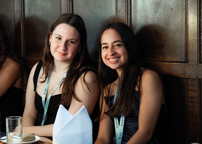 Two female students at their Oxford College graduation, both smiling and happy