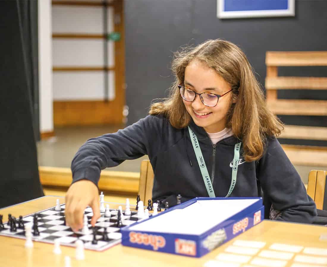 Summer school student smiling and playing chess