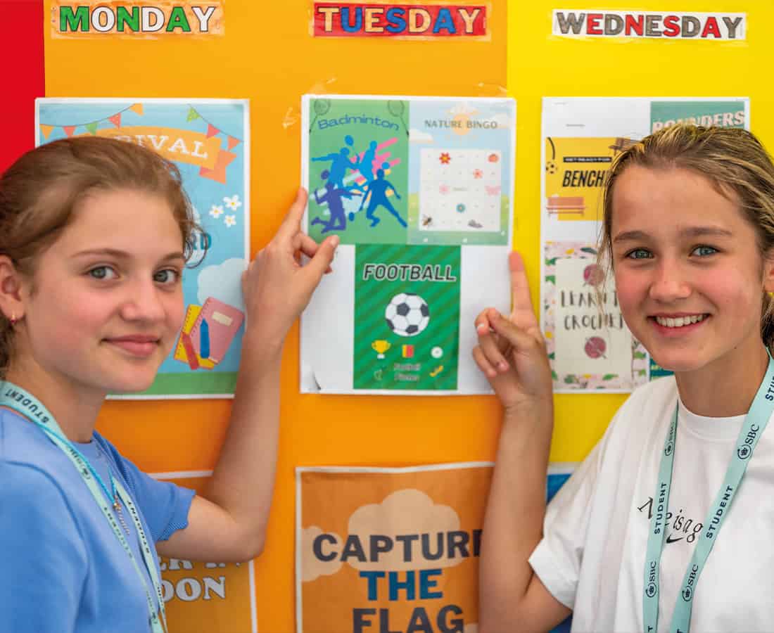 Female students smiling and pointing at a board at SBC Canford