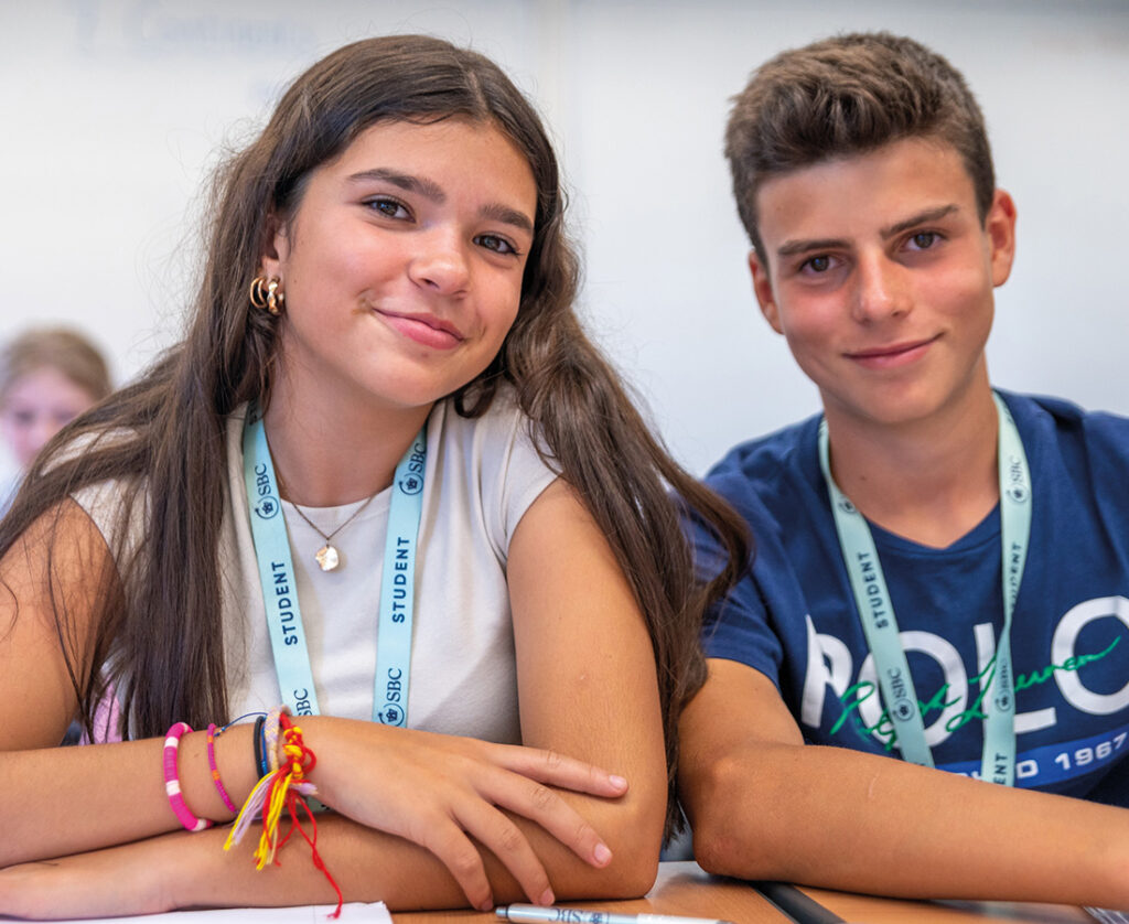 Male and female student in an SBC Canford class smiling at the camera while learning in the classroom