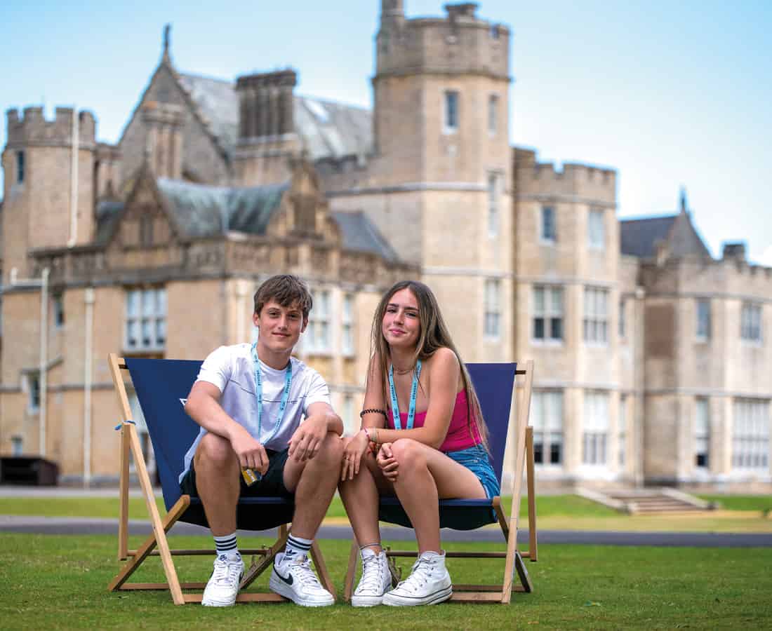 Male and female student sat on deck chairs together on a Summer Boarding Courses