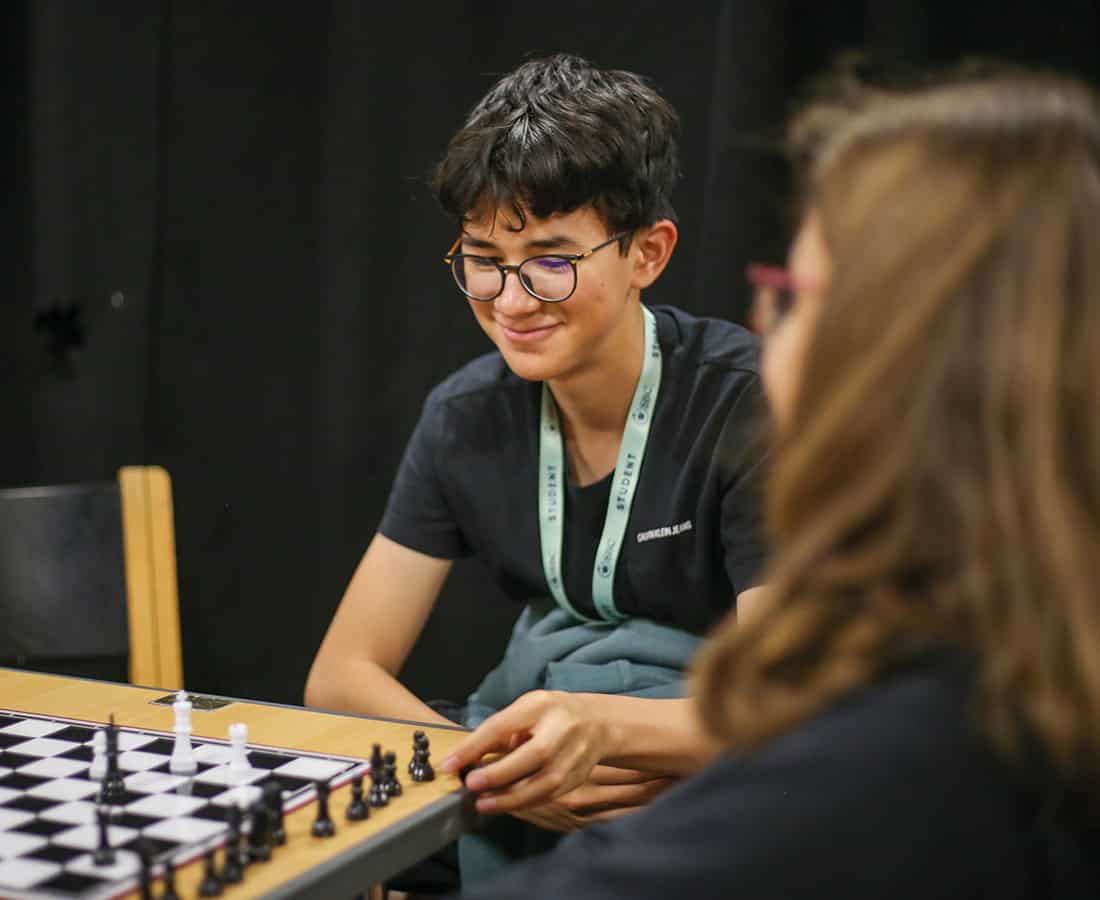Male student playing chess with a female student while smiling at Summer Boarding Courses