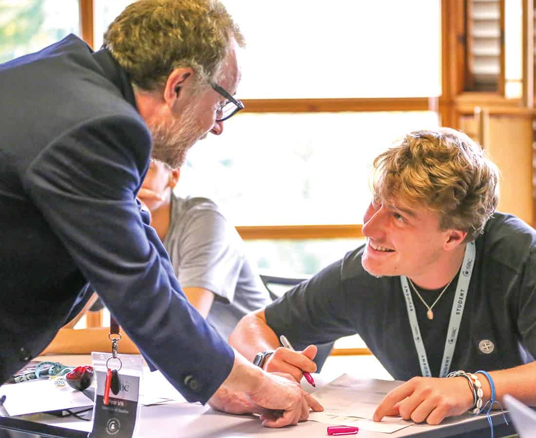 Student and teacher having a conversation at a desk at Cambridge College