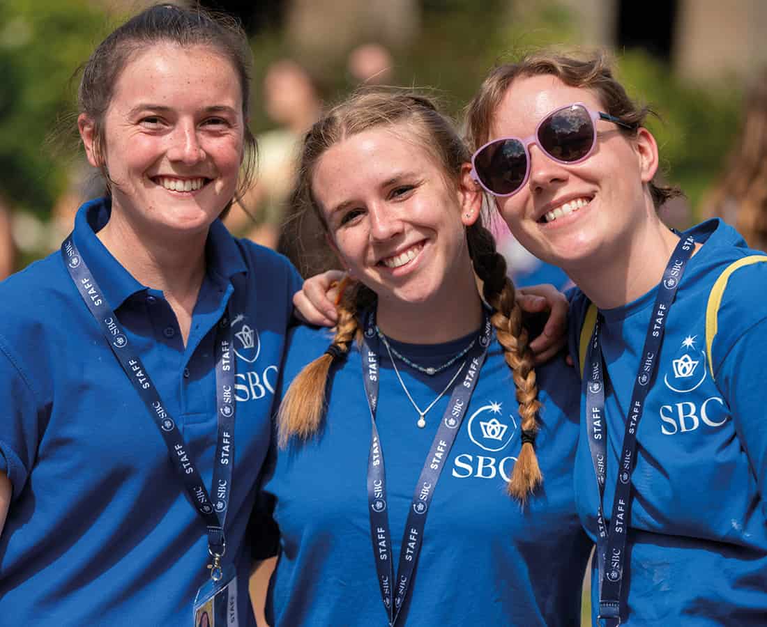 Three female Summer Boarding Courses students smiling at the camera while outside leading an activity