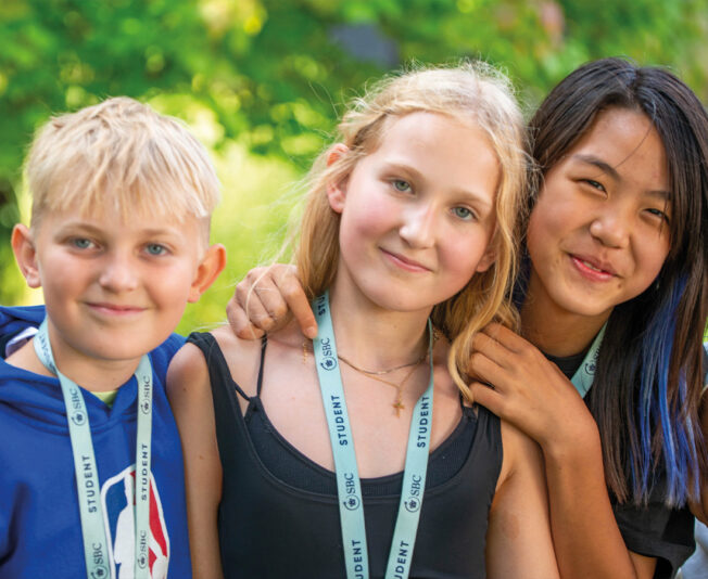 Three smiling SBC students stood outside with their arms around each other