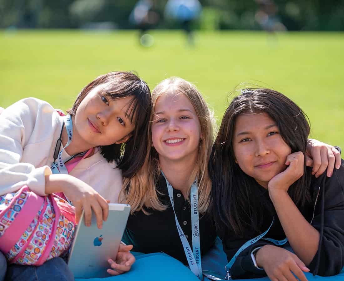 Three you girls smiling on summer school field uk