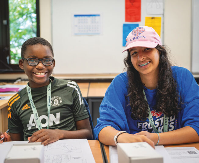 Two SBC Canford summer school students in the classroom together working together and smiling