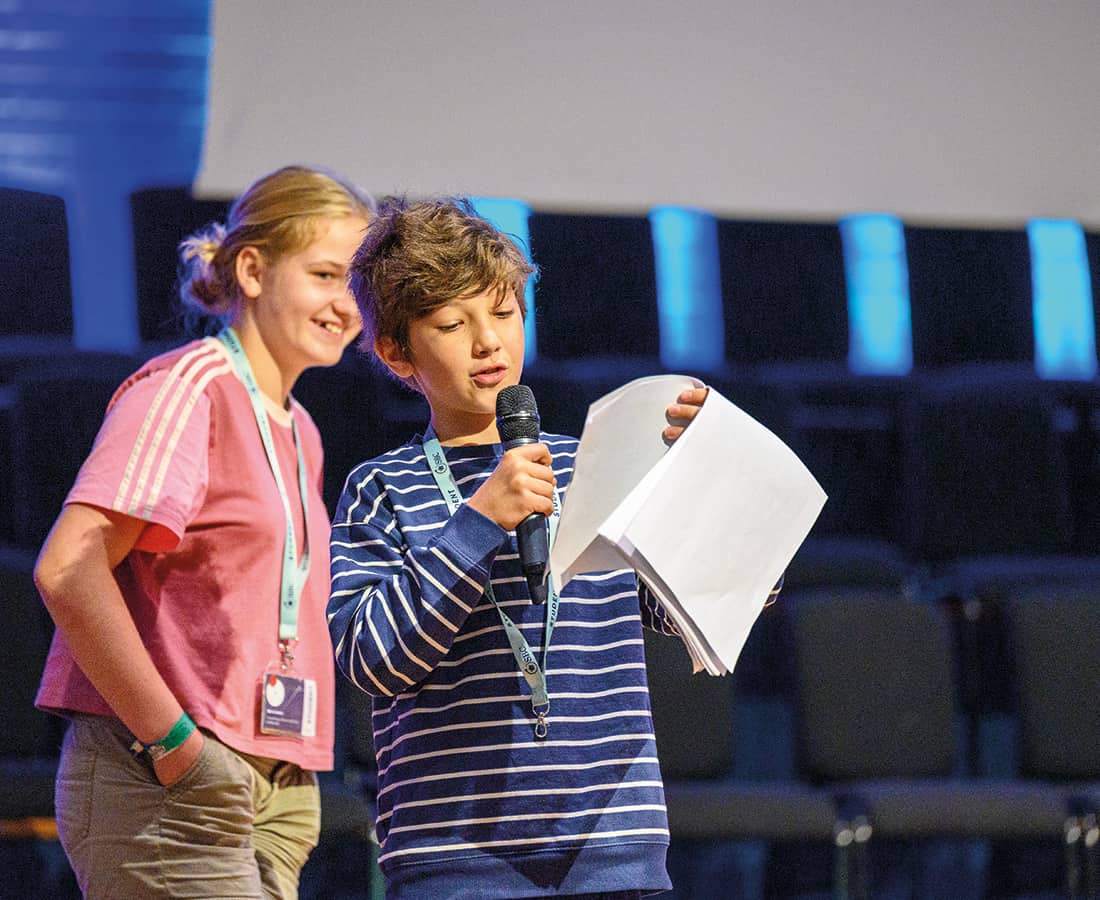 Two students on stage at SBC Canford giving their Time to Shine presentation while smiling