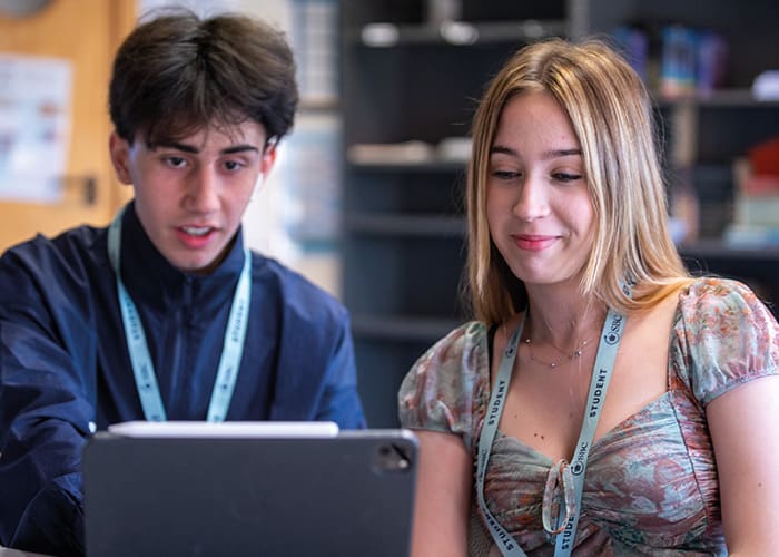 Students-smiling-looking-at-laptop-in-summer-school-lesson-uk