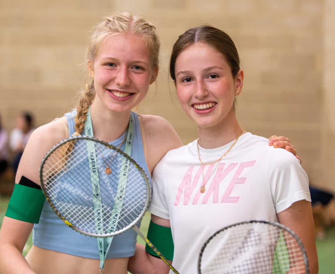 two-smiling-girls-with-tennis-rackets-at-summer-camp.