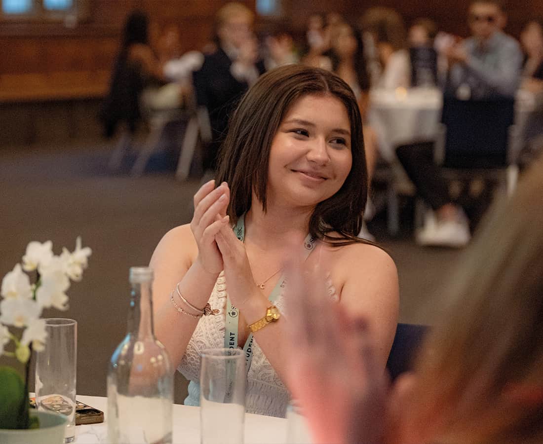 Female student clapping and smiling at Oxford College gradutaiton