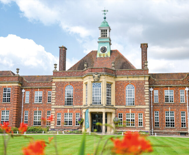 Headington Oxford building with flowers in front and bright green grass, this is where Summer Boarding Courses Headington is held