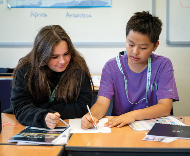 Male and female SBC students sat in a classroom writing and working together