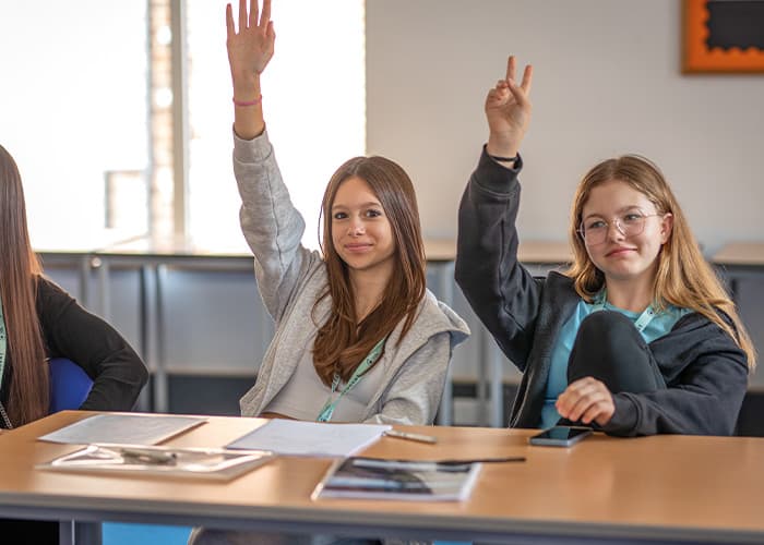 SBC-students-raising-hands-in-class