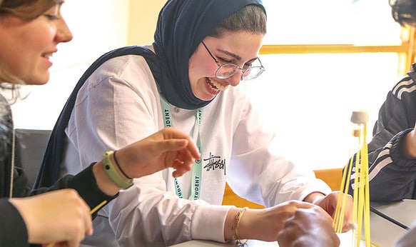 Summer-school-student-smiling-whilst-working-on-a-project-at-SBC-Cambridge-College