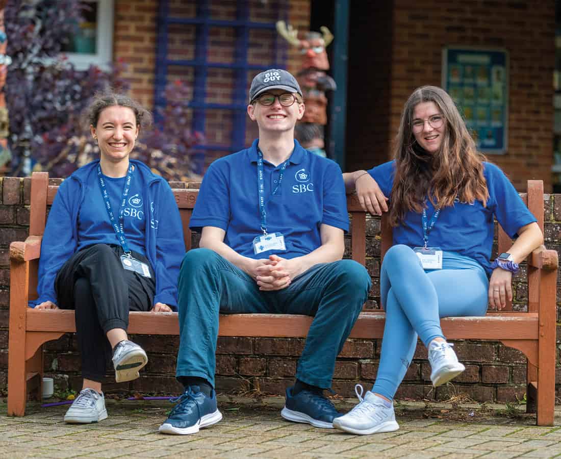 Three staff members sat together at Summer Boarding Courses they are all smiling