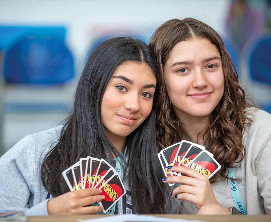 Two female students sat together playing cards while on Social Programme at Summer Boarding Courses