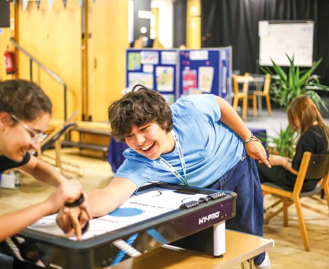 Two students playing table hockey, laughing, smiling and having fun together at Summer Boarding Courses