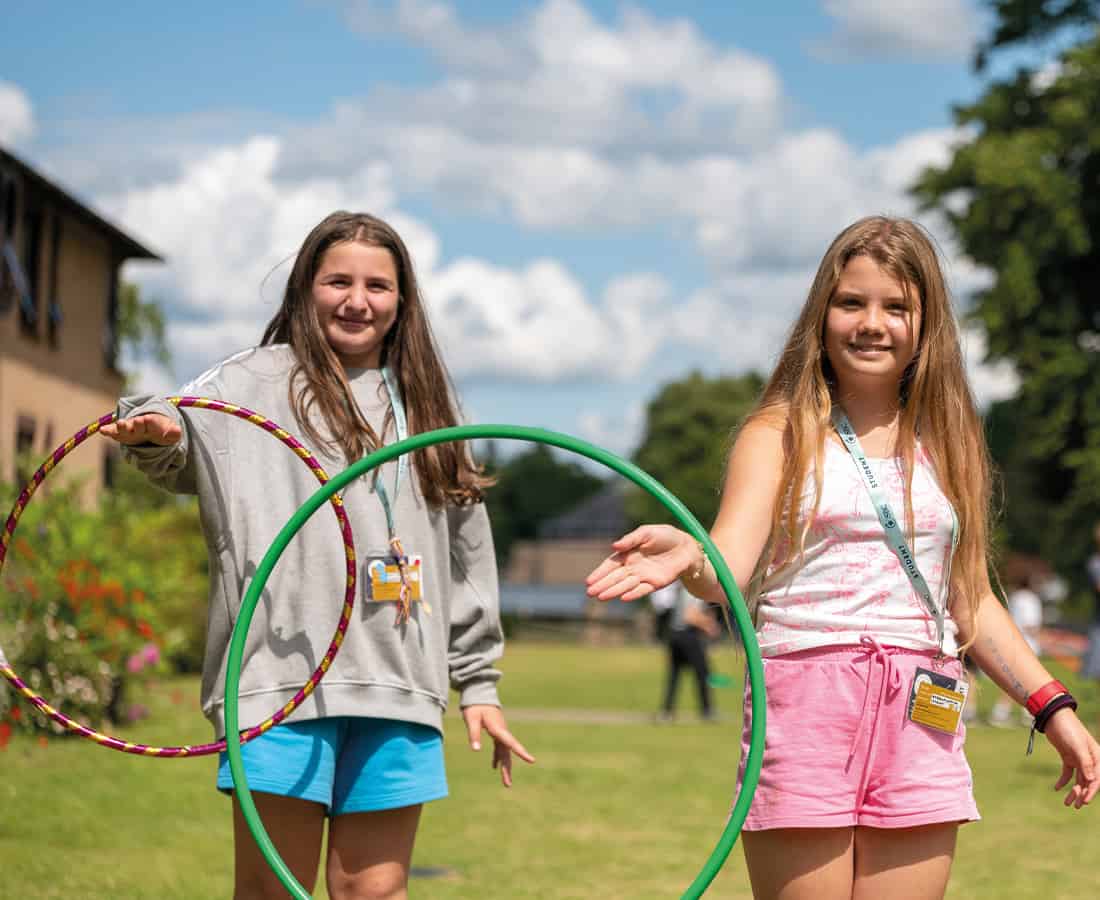 Two younger female students at SBC Canford playing outside in the sunshine and smiling
