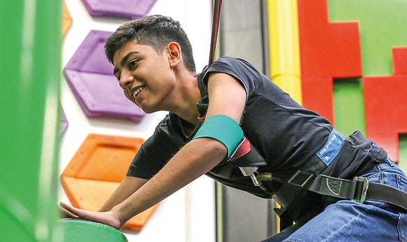 student-smiling-on-climbing-wall-with-SBC-Cambridge-college