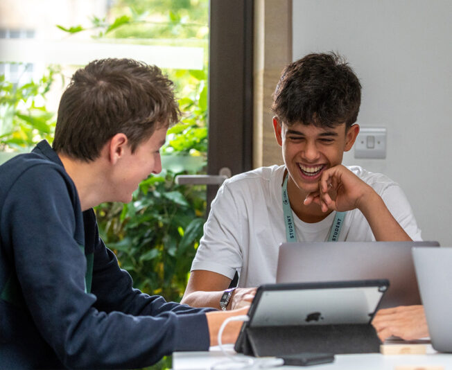 three-sbc-students-smiling-using-laptops-at-oxford-college