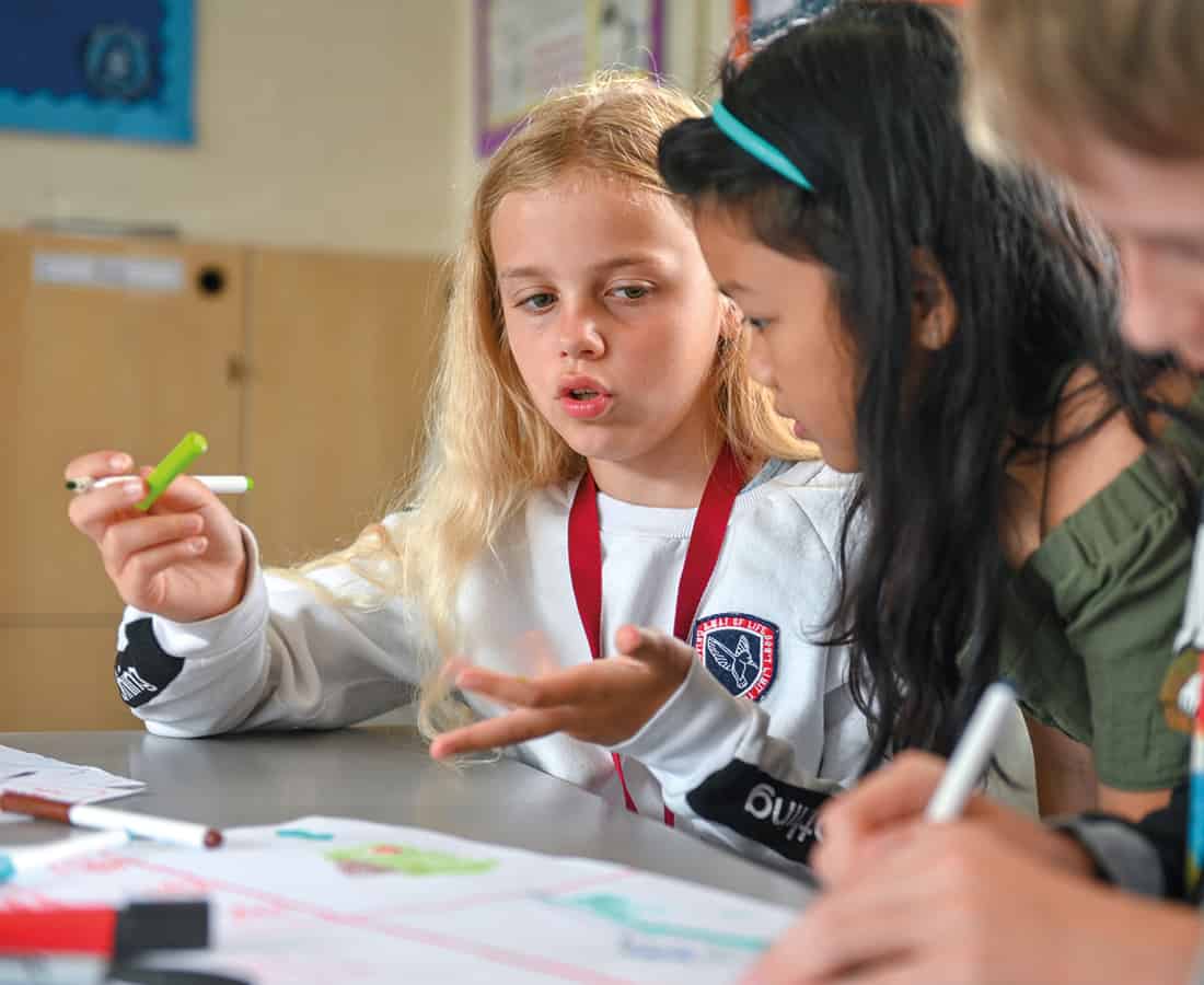 Female students engaged in conversation in their classroom at camp dragon