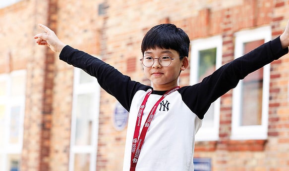 Male-student-at-camp-dragon-with-arms-stretched-high-and-smiling