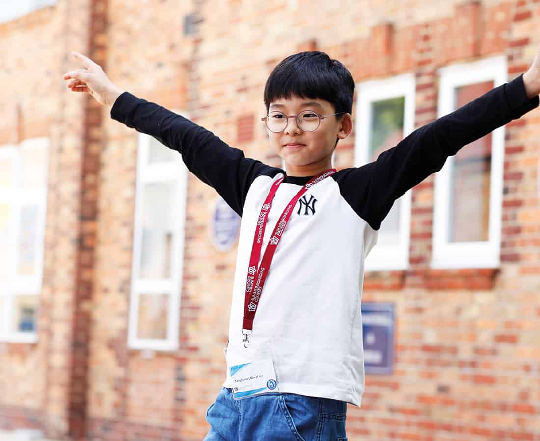 Male-student-at-camp-dragon-with-arms-stretched-high-and-smiling