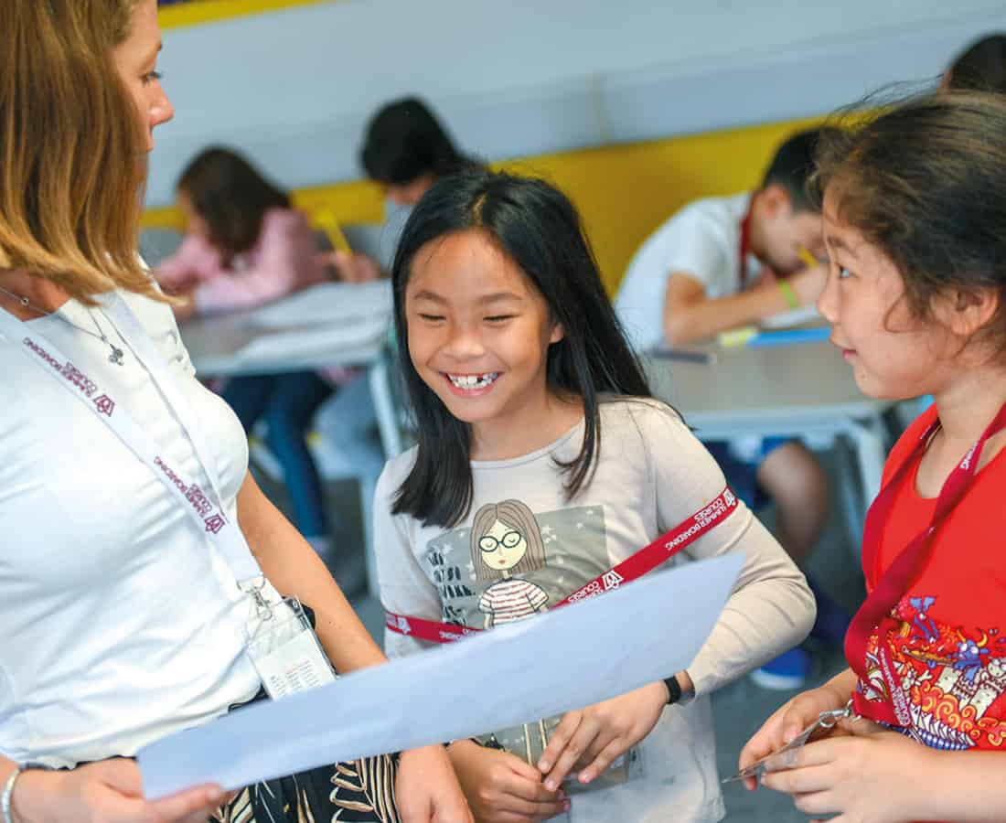 Smiley female student talking to her teacher at camp dragon