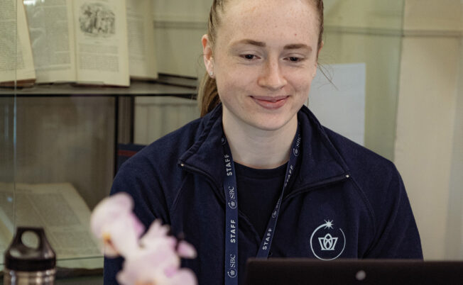 Summer Boarding Courses Office Co-ordinator sat at her desk with a laptop